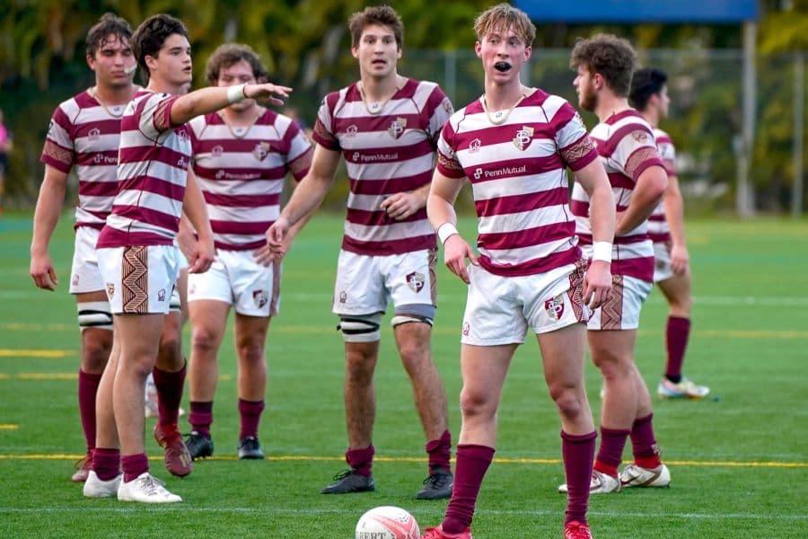 FSU Rugby player lining up a kick with teammates fanned out behind